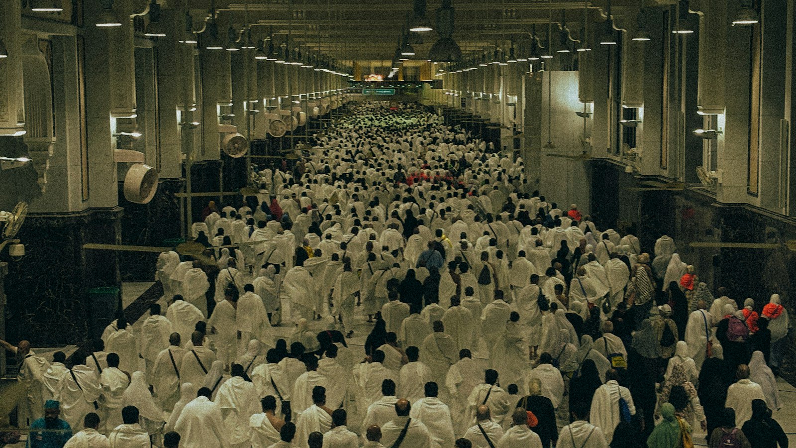 Pèlerins en ihram blanc traversant une galerie de la Grande Mosquée de La Mecque